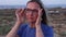 Middle aged blonde woman putting on eyeglasses standing near the sea