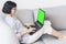 Middle-aged brunette woman with glasses on the gray sofa working on green screen laptop, soft focus