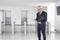 A middle aged businessman in a modern office lobby. Blurred background with elevators and turnstiles and copy space