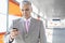 Middle aged businessman text messaging through cell phone at railroad station