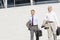 Middle-aged businessmen with briefcases against wall