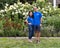 Middle-aged Caucasian man and his Korean wife posing in front of a bed of beautiful flowers in Bar Harbor, Maine.