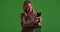 Middle aged Caucasian woman looking at pictures on smartphone on green screen