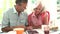 Middle Aged Couple Looking At Digital Tablet Over Breakfast