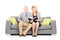 Middle aged couple seated on sofa reading a book