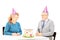 Middle aged couple sitting at birthday party looking at cake