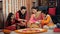 A middle-aged couple and their children decorating a Rangoli together on Diwali