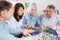 Middle-aged family elderly collects jigsaw puzzles at the table in the room