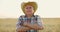 Middle aged farmer standing in harvest ready wheat field at sunset.Man with crossed arms smiling