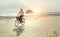 Middle-aged female dressed light summer clothes riding old vintage bicycle with front basket on the lonely low tide ocean white