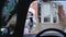 Middle-aged female driver scraping and cleaning snow off car windshield.