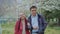 A middle-aged loving couple approaches a tree in the park and talks,the man picks flowers from the tree