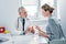 middle aged male doctor pointing at pills to female patient at table