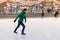 Middle aged male wears figure skates, being at ice rink in winter park, has fun with friend. Athlete speed skater demonstrates hi