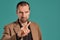 Middle-aged man with beard and mustache, wears black shirt and brown jacket posing against a blue background. Sincere