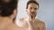 Middle-aged man critically looking at his beard in mirror, morning ritual