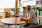 middle-aged man, elegant, modern, wearing headphones sits in street cafe