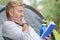 Middle-aged man engrossed in book by tent