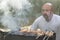 middle-aged man enjoys cooking meat on the grill. leisure, food, people and holidays concept - happy young man cooking meat on bar