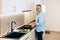 Middle aged man happy to cook something tasty and healthy for his family. He standing by stove, stews vegetables in a