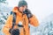 Middle-aged Man with a hot drink cup and a thermos flask dressed bright orange softshell jacket drinking while he trekking winter