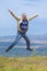 Middle-aged man jumping arms and legs spread out against the background of the view from the mountain