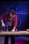 Middle-aged man in jumpsuit fixing red plastic kids skateboard in home workshop