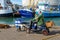 A middle aged man on a mobility scooter taking his dog for a walk on the quayside or dock