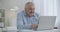 Middle-aged man with moustache is typing text on keyboard of laptop, browsing internet sites, working with notebook from