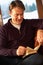 Middle Aged Man Relaxing With Book Sitting On Sofa