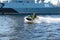 A middle-aged man rides a jet ski on the Neva River in the center of St. Petersburg. Warships on the background. Sunny day. Summer