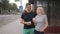 A middle-aged man and woman drink coffee from paper cups, stand at a public transport stop waiting for the bus they need