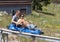 Middle-aged married couple enjoying a ride in a blue sled on a rollercoaster-like track in Vail, Colorado.