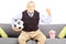 Middle aged sport fan holding a soccer ball and watching sport