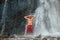 Middle-aged topless sincerely laughing man standing under the mountain river waterfall and enjoying the splashing Nature power.