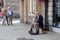 A middle aged well dressed street busker playing the guitar
