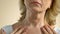 Middle-aged woman carefully examining wrinkled skin of her neck and chest