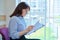 Middle aged woman with clipboard sitting in office near window.