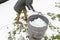 middle-aged woman is collecting snow in a barrel with a shovel,natural resources