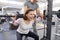 Middle-aged woman doing sports exercise in fitness center. Personal gym trainer assisting mature woman. Health fitness sport age