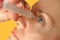 Middle aged woman drops eyes. Macro closeup image of face. Medical procedure at home. Girl holding eyedropper bottle and dropping