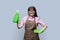 Middle aged woman in gloves apron with organic detergent on grey background