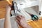 Middle aged woman hands sewing linen cloth on stitching machine, from above overhead top view