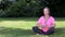 Middle aged woman in her forties outside cross legged practicing yoga in prayer or lotus position