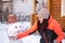 Middle aged woman by herself making snowman on backyard of cottage in daytime while snow is falling down with wooden