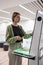 Middle-aged woman library visitor using self-service machine for borrow or return book