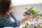 Middle-aged woman making bouquet of lilac branches, close-up female arranging flowers bunch in vase