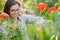 Middle-aged woman in nature cutting flowers red poppies