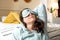 Middle aged woman in pajamas and sleep mask sitting relaxed on bed at home