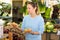 Middle-aged woman purchaser holding fresh potatoes in grocery store